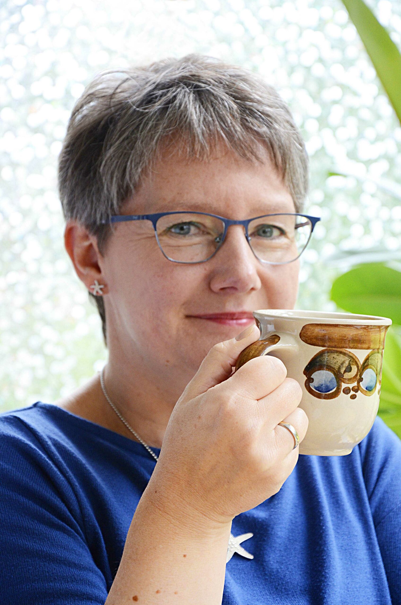 Marion Schmitz lächelt mit Kaffeetasse in der Hand